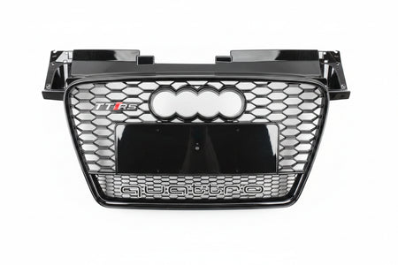 A glossy black Audi Q5 TFS quattro front grille with the four-ring logo and 'quattro' text, photographed from above on a gray asphalt surface.