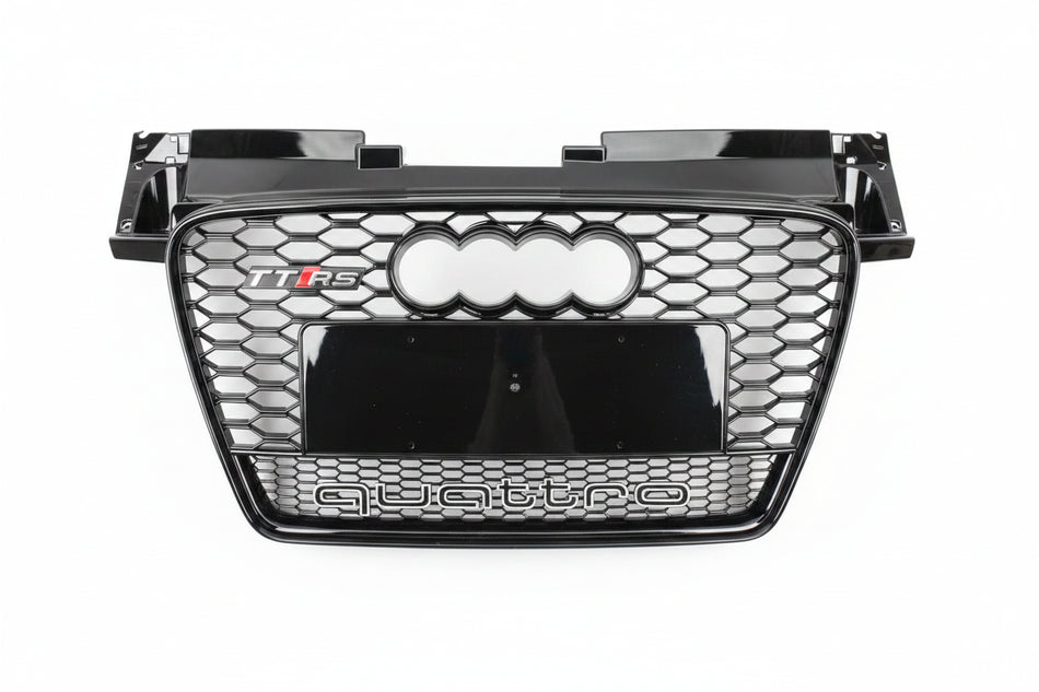 A glossy black Audi Q5 TFS quattro front grille with the four-ring logo and 'quattro' text, photographed from above on a gray asphalt surface.